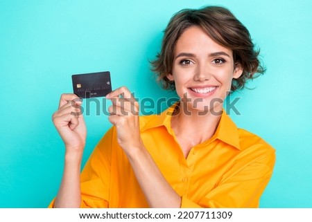 Closeup photo of young adorable pretty nice girlish lady hold debit card can get salary right now wireless payment isolated on cyan color background