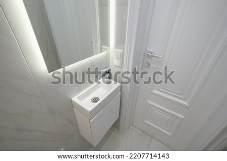 Small white hand wash sink and vanity mirror in bathroom interior