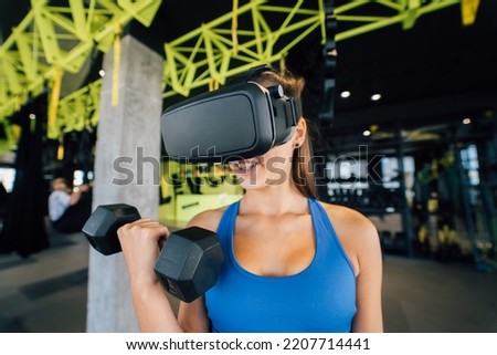 Woman wearing glasses of the virtual reality exercising with dumbbells
