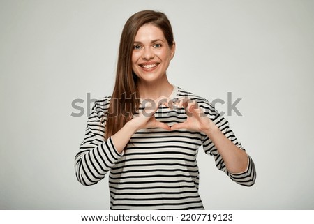 Smiling woman making heart shape with her hands. Isolated portrait.