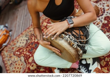 A young beautiful woman plays a hand drum Royalty-Free Stock Photo #2207720869