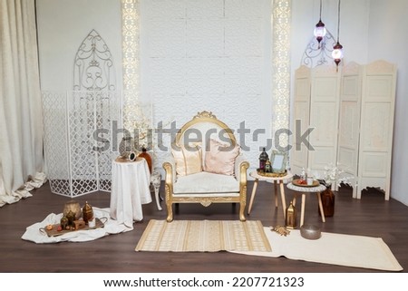 light armchair with tables in oriental style. oriental photo zone in a photo studio with lamps and fabrics. photo zone in Arabic style with carpets and flowers