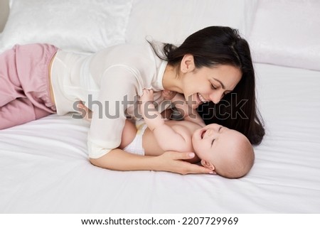 mother plays with her baby girl in the bedroom.