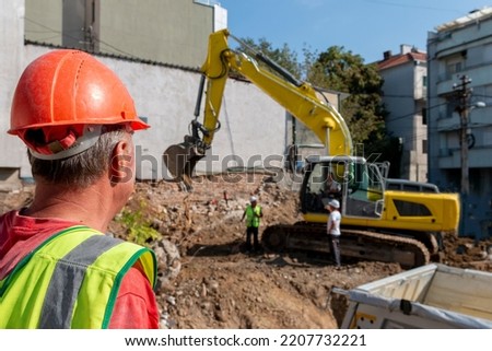 Site manager   standing at the construction site of a private property, supervising, inspecting or overseeing the work progressProcess of demolition of old building dismantling.  Royalty-Free Stock Photo #2207732221