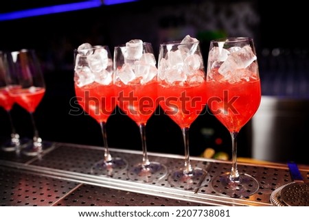 Glasses with delicious pink cocktail and ice on the bar counter