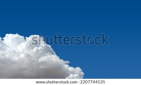 A large cumulus clouds floating against a clear blue sky  Royalty-Free Stock Photo #2207744535