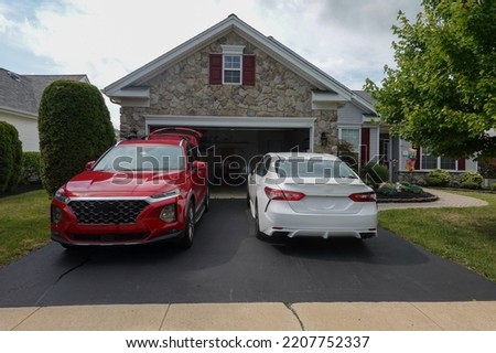 Driveway view of the stone facade of a house with two cars facing in different directions Royalty-Free Stock Photo #2207752337