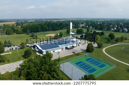 An aerial view looking at a rural sports building and facility with solar panels installed across the roof. Royalty-Free Stock Photo #2207775795