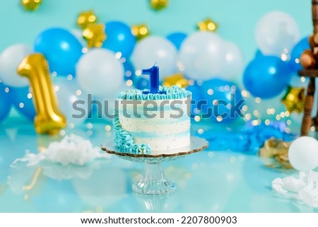 Blue and white birthday cake with balloons in the background. Photo set decoration for photo shoot.