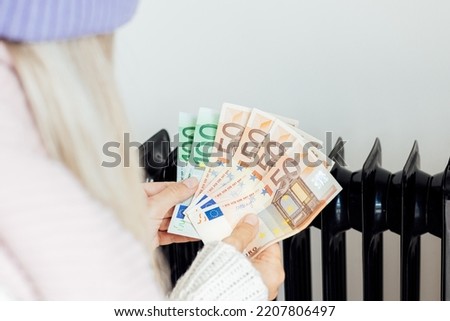 heating, energy crisis in Europe and consumption concept. Woman counting cash money for pay utility bills at home. Rising costs in private households for gas bill due to inflation and war