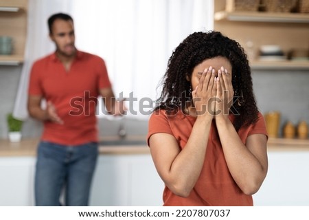 Sad angry millennial black male scolding to crying offended female in kitchen interior, free space. Quarrel, scandal, relationship problems and domestic violence at home during covid-19 pandemic Royalty-Free Stock Photo #2207807037