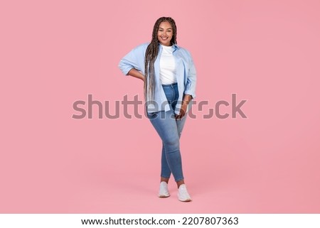 Pretty African American Plus Size Lady Model Posing Wearing Large Size Clothes Standing Smiling To Camera Over Pink Studio Background. Fashion And Style. Full Length Royalty-Free Stock Photo #2207807363