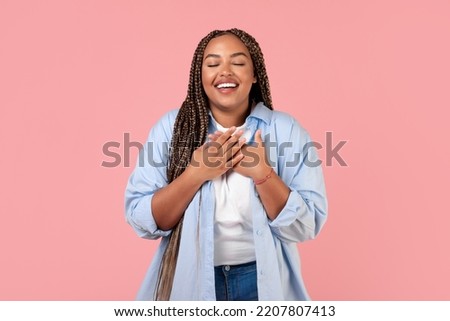 Grateful African American Woman Pressing Hands To Chest Standing Posing With Eyes Closed Over Pink Background. Studio Shot Of Obese Lady Expressing Gratitude. Happiness And Kindness Concept