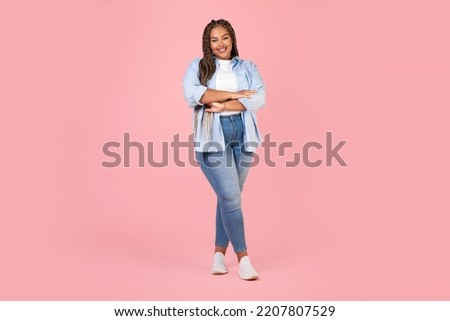 Attractive African American Female Posing Wearing Plus Size Clothes, Standing Crossing Hands And Smiling To Camera On Pink Background In Studio. Body Positive Concept. Full Length Shot
