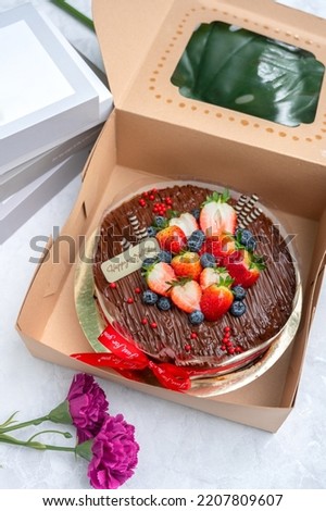 Happy Birthday with a delicious chocolate cake topped with fresh strawberries and blueberries.