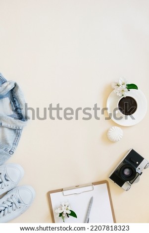 Vacation planning concept still life. Clothes, a cup of coffee, a camera and a notepad with a pen on a beige background with a copy space