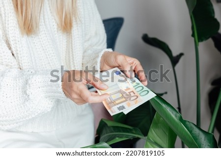 Unhappy Young woman wearing warm clothing at home and counting cash money. Energy crisis in Europe due to inflation and war. Increase in the price of natural gas for home heating. 