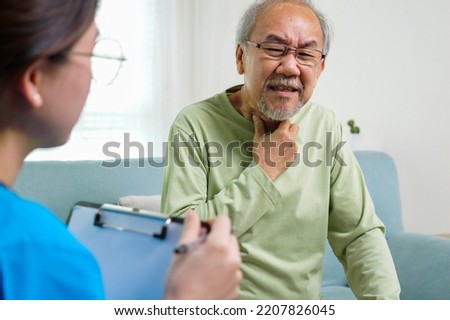 Young doctor examining senior patient at home visit, Senior man consulting medicine with pharmacist, Caregiver nurse taking care of elderly grandfather sitting on sofa at home, Medical service concept