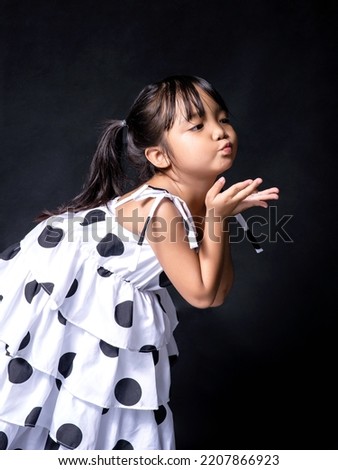 Picture of a girl she looks cute and bright, making a kissing gesture.