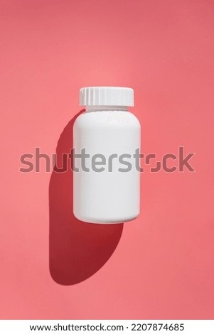White plastic pills bottle, vitamins or food supplemets. Container with medication pills on pink background with sun light and shadows Royalty-Free Stock Photo #2207874685