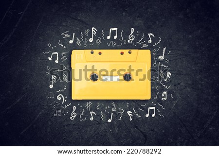 yellow retro Cassette tape over blackboard. top view. music sketches