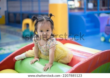 Pretty little kid girl in dress sit on toy at theme park, playing with toys. beautiful baby girl sitting play toys on blur background. Quality picture. concept happy mom and daughter.
