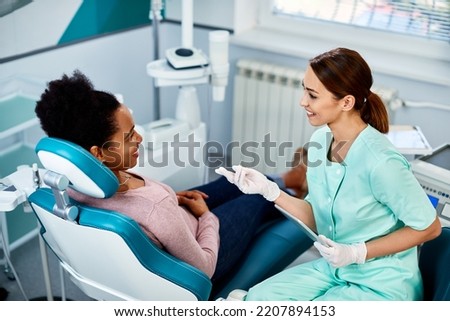 African American woman communicating with her dentist during dental procedure at dentist's office. Royalty-Free Stock Photo #2207894153