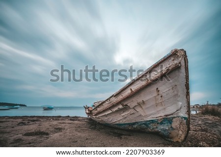 Long exposure photography, abandoned ship on land and moving clouds at sky as a background