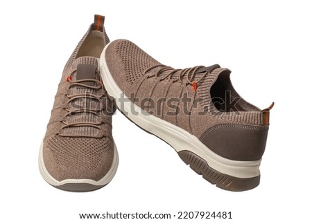 Closeup of a pair of modern brown sneakers or sports shoes isolated on a white background. Clipping path. Elegant and trendy mans shoes. Macro.