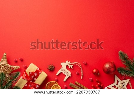 Christmas decorations concept. Top view photo of wood ornaments baubles pine branches craft paper giftbox wicker star dried orange slices mistletoe cinnamon on isolated red background with copyspace