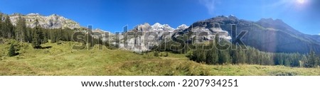 Snow big mountains in the sunny day. Summer blue sky big mountains. Forest, green trees and fields. Nature landscape with mountains and forest.  Royalty-Free Stock Photo #2207934251