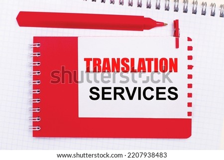 On a white notepad, a red pen, a red notepad and a white sheet of paper with the text TRANSLATION SERVICES