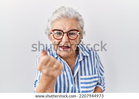 Senior woman with grey hair standing over white background angry and mad raising fist frustrated and furious while shouting with anger. rage and aggressive concept.  Royalty-Free Stock Photo #2207944973