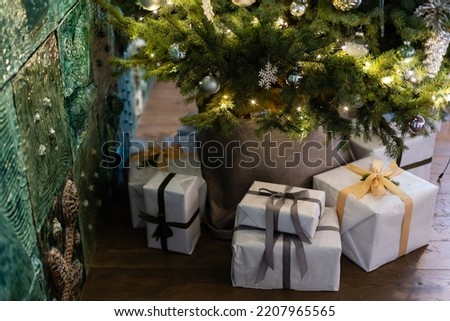 Beautiful Christmas gift boxes on floor near fir tree in room.
