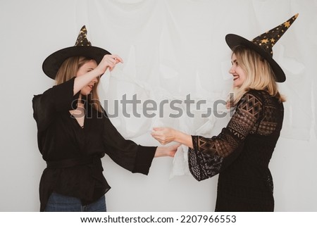 Two beautiful women wearing witch hat, halloween costume on white background