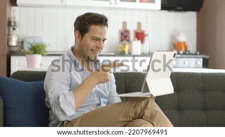 Smiling happy young man working on tablet computer, surprised to see it on screen. Online booking service, app promotion and advertising concept. Win at the amazing online casino or lottery game.