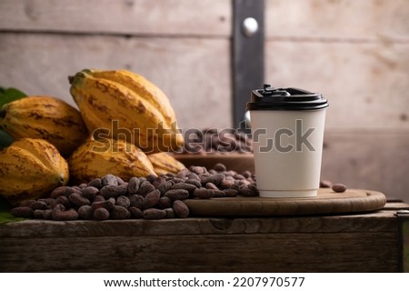 Takeaway White paper hot cocoa cup on Ripe cocoa pod and nibs, cocoa beans set up background
