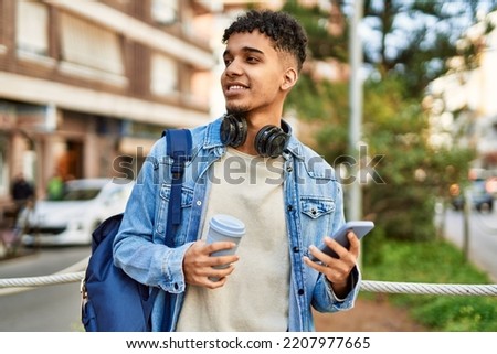 Hispanic young man using smartphone drinking a coffee at the street Royalty-Free Stock Photo #2207977665