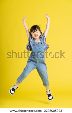 full body image of beautiful asian baby girl on yellow background Royalty-Free Stock Photo #2208005023