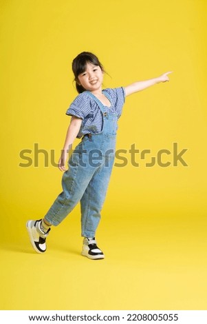 full body image of beautiful asian baby girl on yellow background Royalty-Free Stock Photo #2208005055