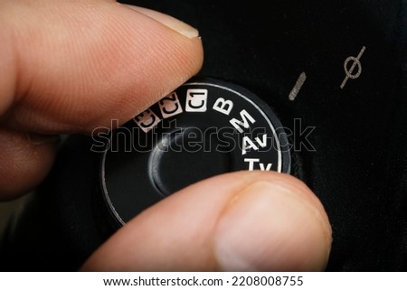 Fingers selecting manual mode on a professional camera. man putting the manual mode on the photo camera. Dial with manual mode in digital photography cameras. Man selecting manual mode Royalty-Free Stock Photo #2208008755