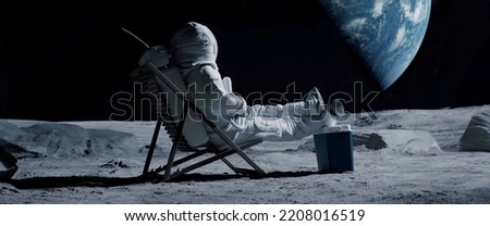 Lunar astronaut chilling on a beach chair with refrigerator bag on Moon surface, enjoying view of Earth Royalty-Free Stock Photo #2208016519