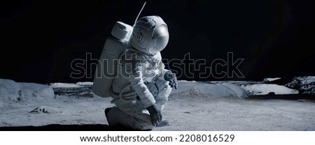 Full portrait of Caucasian female lunar astronaut finds something and kneels while exploring Moon surface Royalty-Free Stock Photo #2208016529