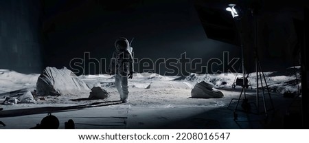 WIDE Behind the scenes - male actor in astronaut waking towards the camera on on a Moon Lunar movie shooting set Royalty-Free Stock Photo #2208016547