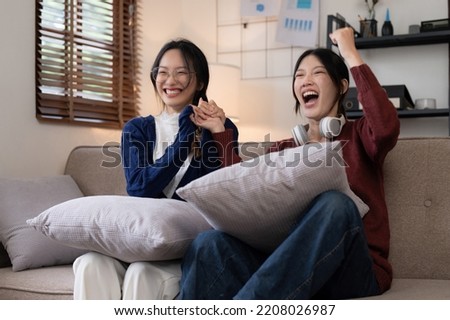 Two Young woman cheering together for sport on TV in cozy living room at home.