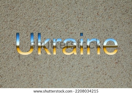 Inscription «Ukraine». Text in Ukrainian style, is lying on a gray granular surface or background. Patriotic letters in colores of Ukrainian flag. Сonceptual idea. Ukraine's Independence Day