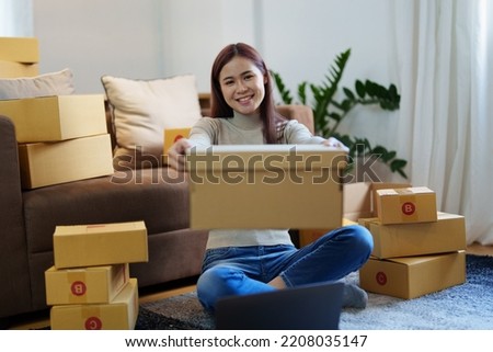 Portrait of a small startup Asian female entrepreneur SME owner picking up product before packing it in an inner box with a customer. Online Business Ideas and Freelance.