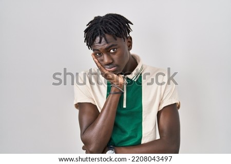 African man with dreadlocks standing over isolated background thinking looking tired and bored with depression problems with crossed arms. 