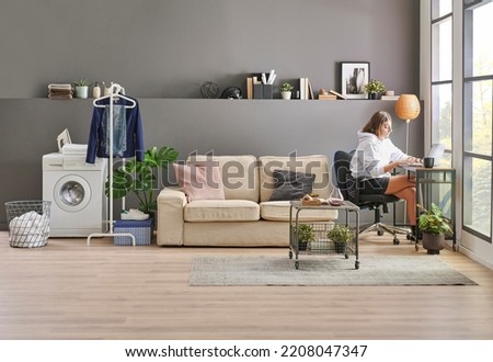 Teenage girl working and study lesson in her room. Grey wall background, sofa and laundry style.