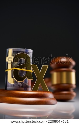 Judge's gavel with dollars in roll with single word tax  against gray background Royalty-Free Stock Photo #2208047681